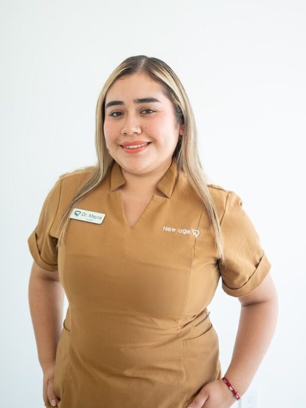 A woman wearing a brown uniform with a name tag that reads "Dr. Espin" stands in front of a plain white background, smiling at the camera.