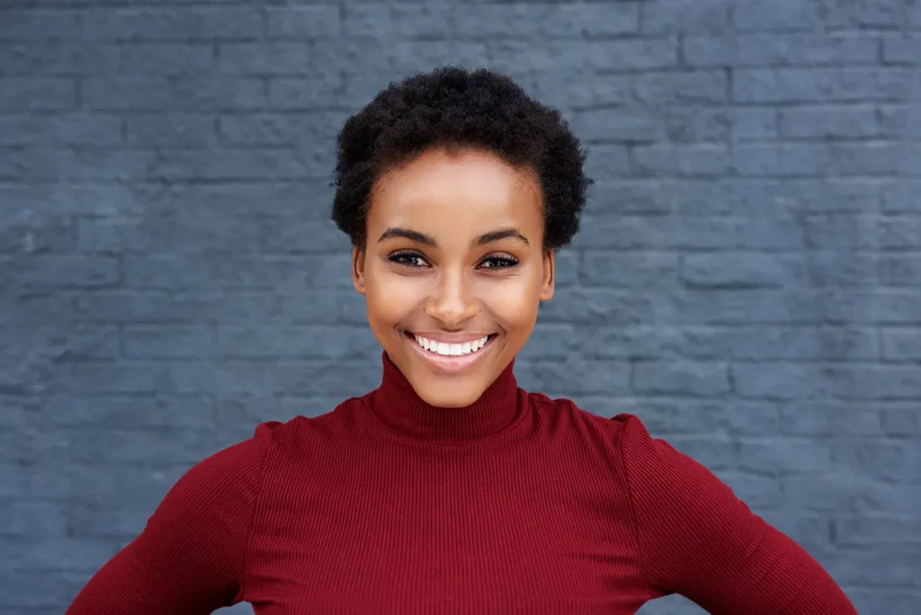 17 fun tooth facts for a Healthy Mouth 3 A smiling black woman in a red turtleneck.