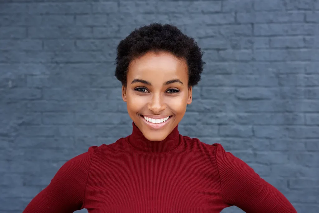 A smiling black woman in a red turtleneck.