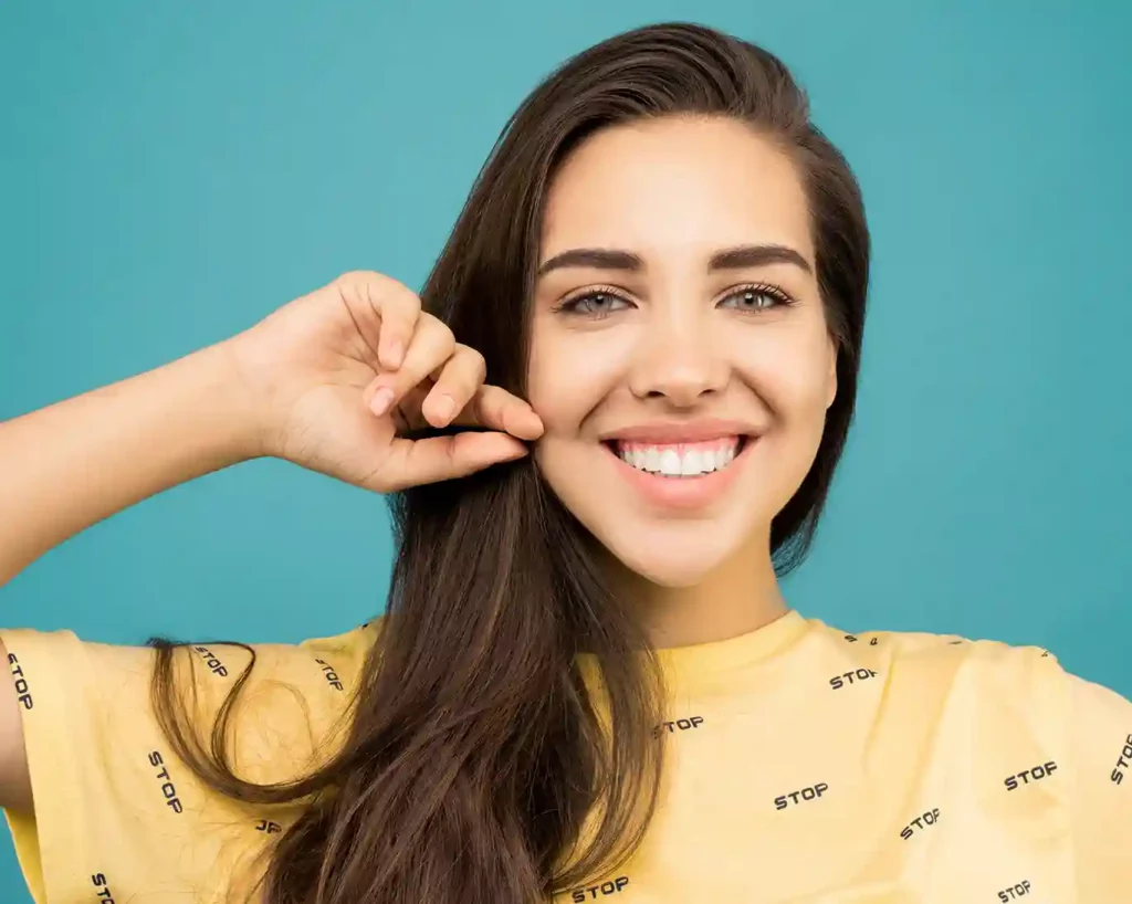 Questions About Dental Veneers in Tijuana 9 A young woman seeking answers about dental veneers in Tijuana listens attentively with her hand on her ear.