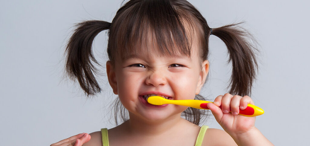 A little girl is brushing her teeth in Tijuana.
