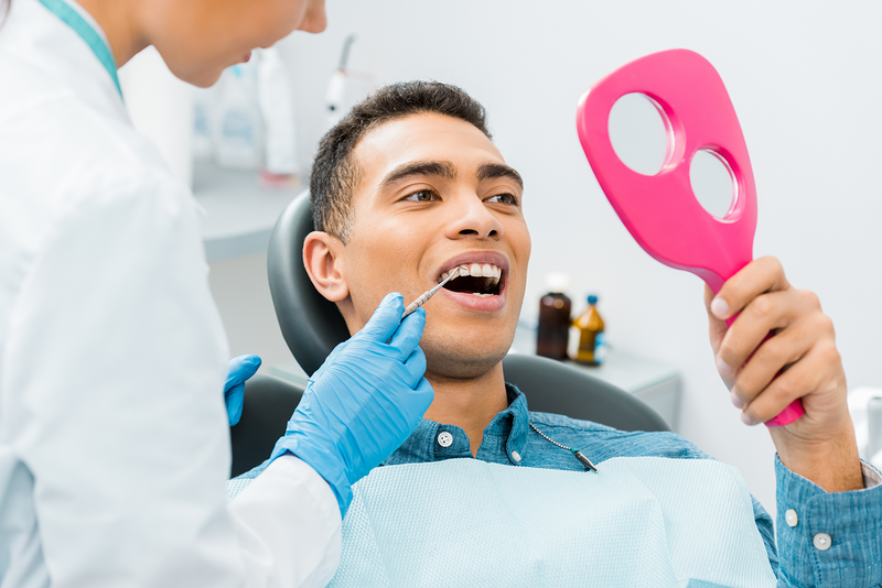 A man is having his teeth examined by a dentist to achieve the smile of his dreams.