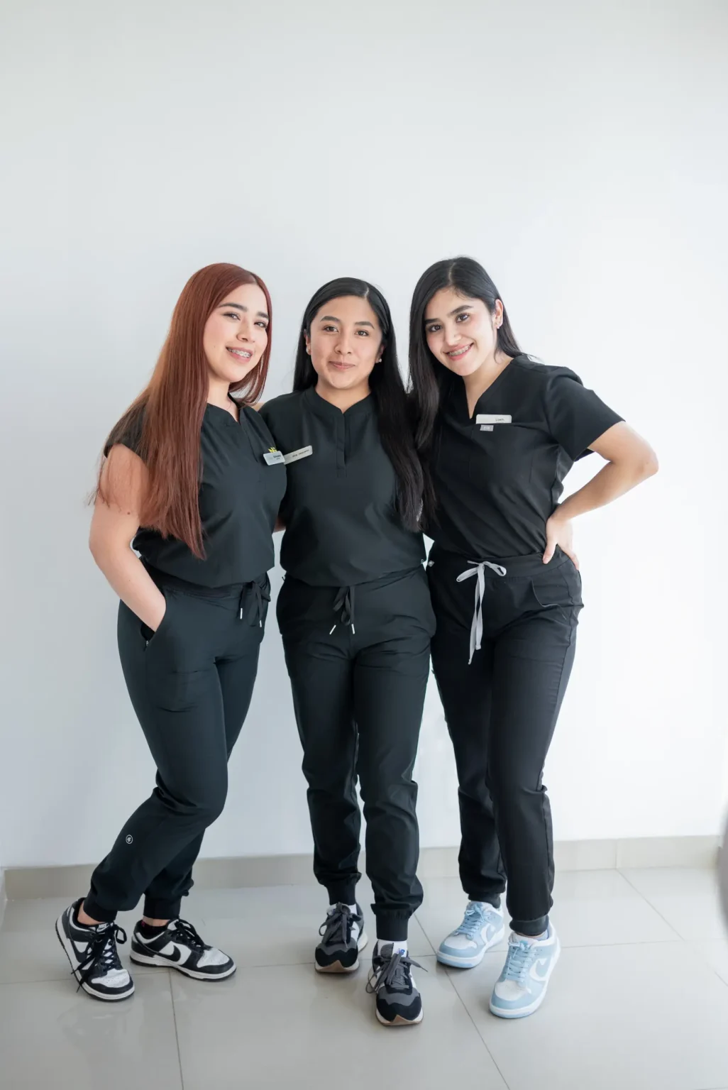 Three women in black uniforms posing together.