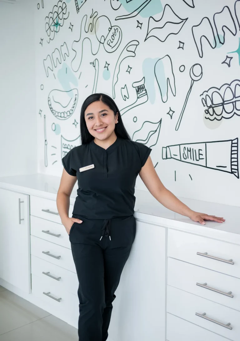 A woman in black medical scrubs standing in front of a whiteboard with playful doodles.