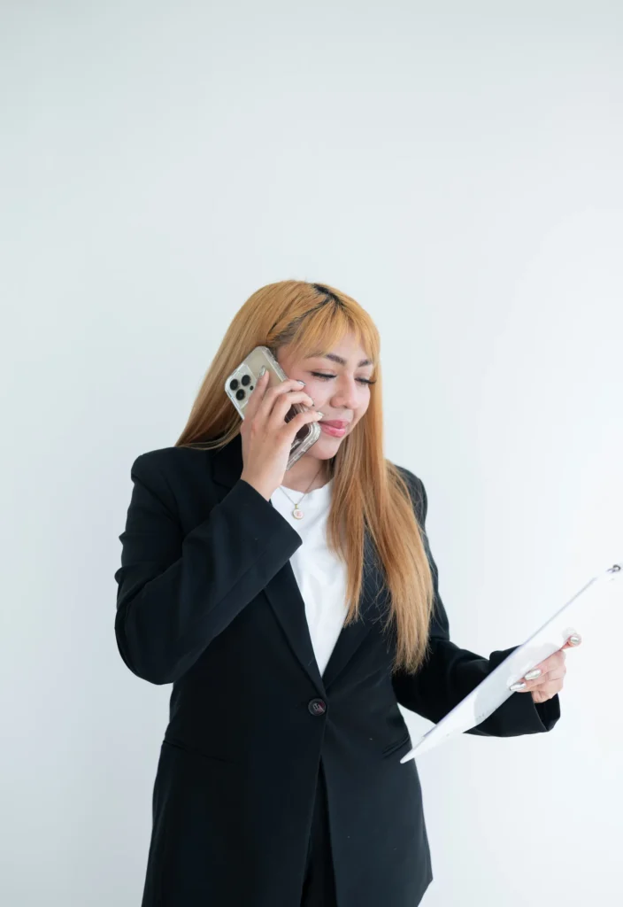 A professional woman talking on a mobile phone while holding a document.