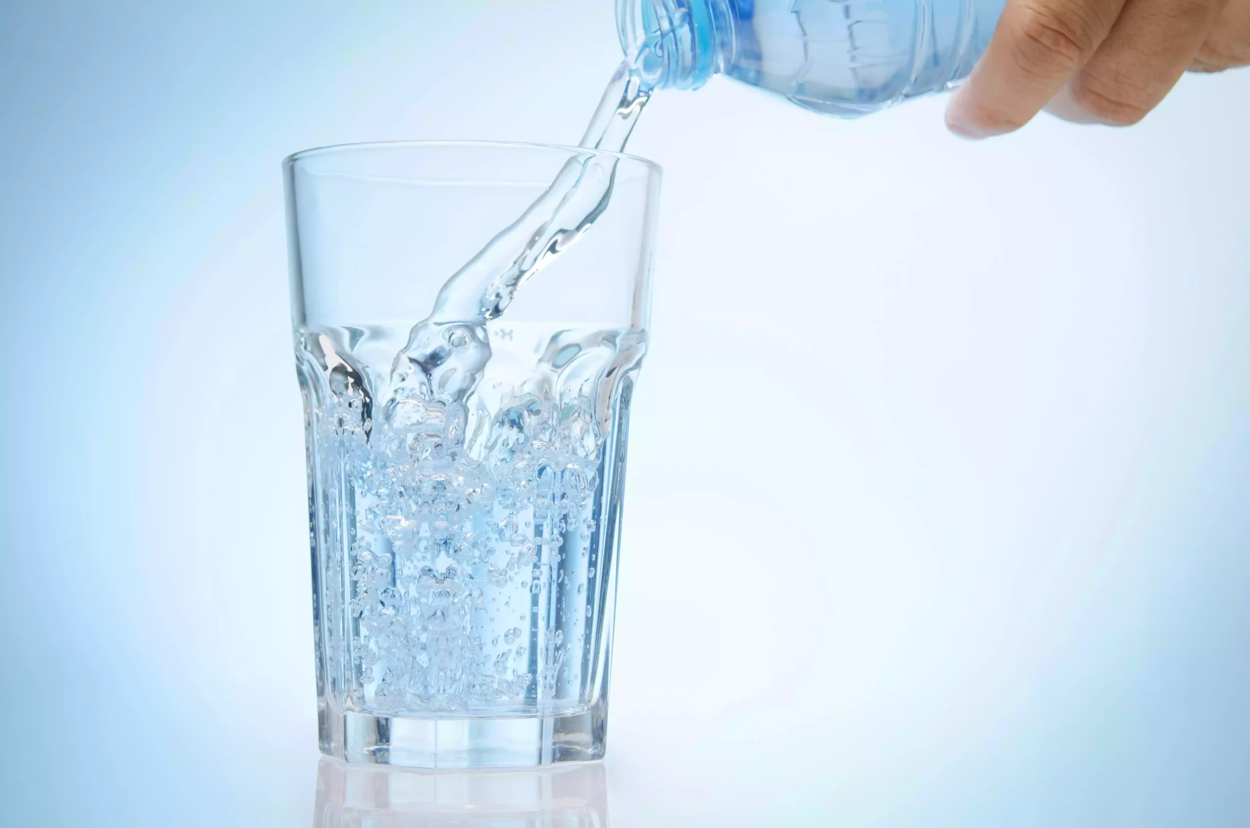 A person pouring water into a glass to alleviate dry mouth.