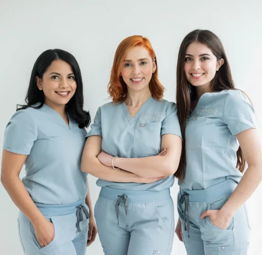 Three women in blue scrubs posing for a photo at home.